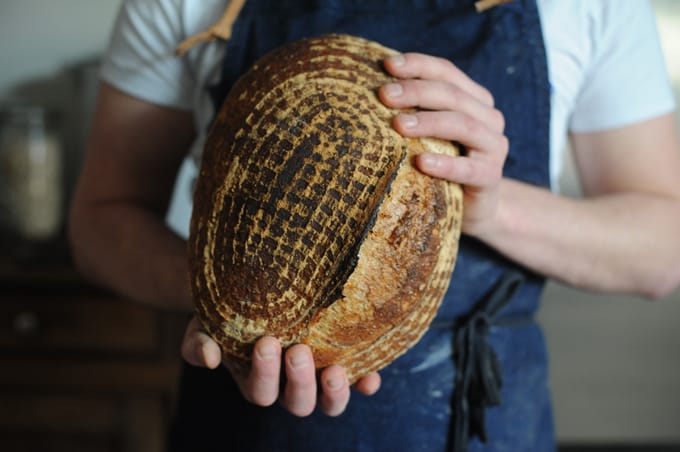 male baker holding patterned loaf