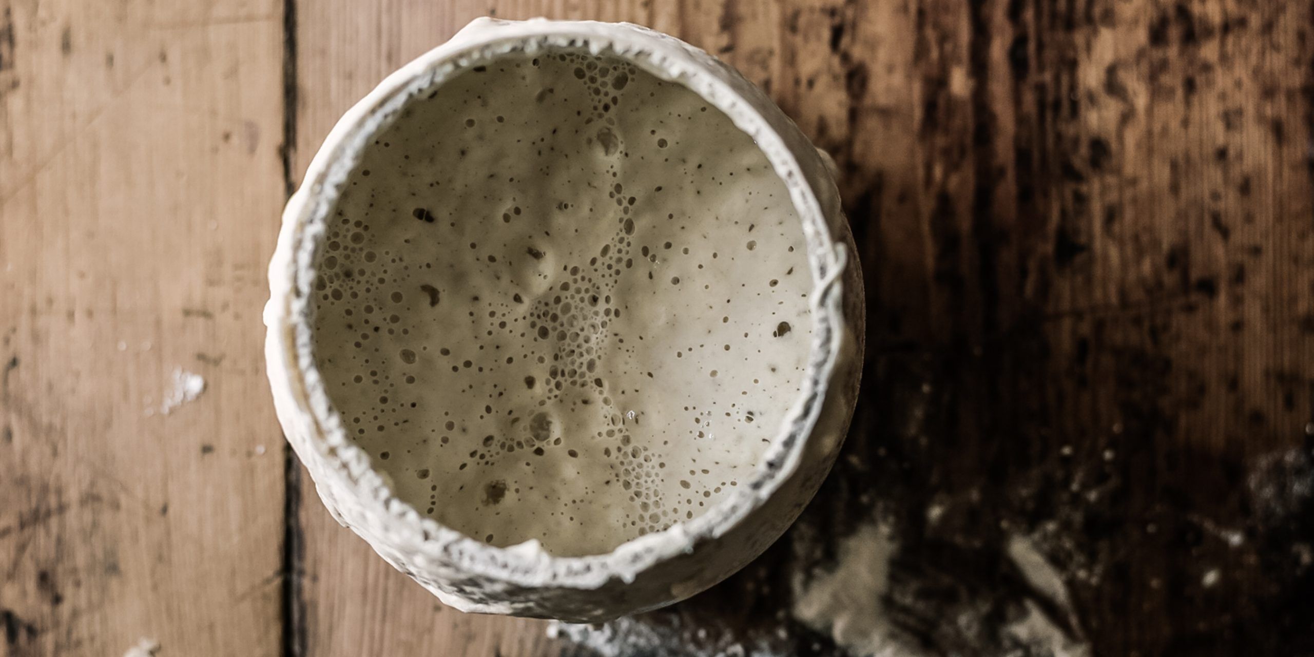 white sourdough starter a photo showing what a healthy starter looks like on the table in a pot
