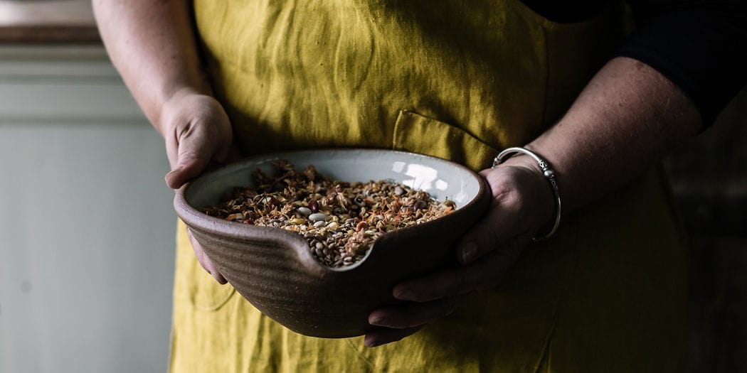 grains and blend in a bowl being held by a persons hands