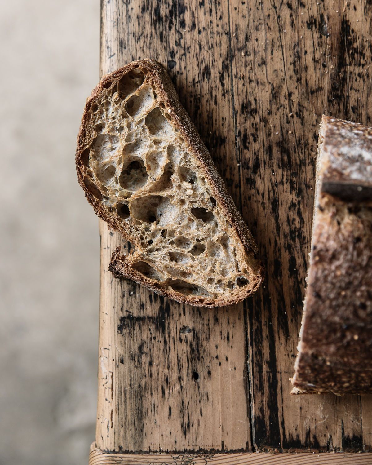 A close up of a slice of crusty soudough is on top of a rustic wooden table