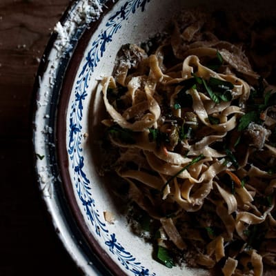 Bowl filled with fresh pasta, topped with fresh herbs and cheese shavings. Tuscan lemon and courgette pasta.