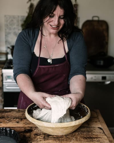Vanessa Kimbell teaching people at the table stretching dough and sharing how you make real sourdough bread