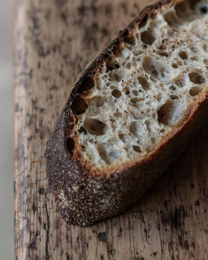 A slice of sourdough bread on a wooden table, a close up of the bubbles in the baked slice. Aldehydes in Sourdough Baking