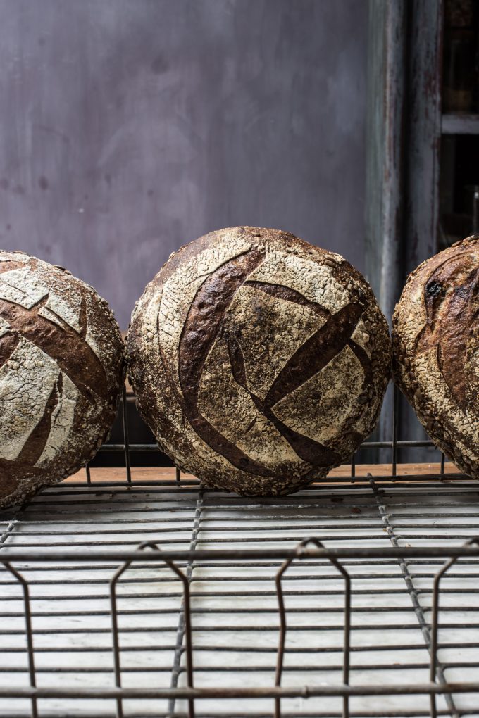 Three sourdough boules standing on their side in a wire basket.