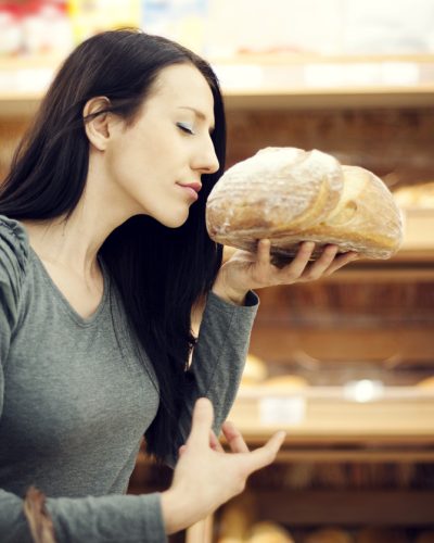 woman smelling loaf of freshly baked bread