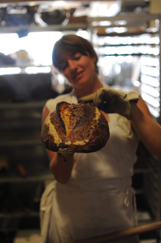 Retarded bread out of the oven being held by a baker in oven gloves in the bakery that made retired bread famous Tartine bakery photo by Vanessa Kimbell