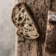 A close up of a slice of crusty soudough is on top of a rustic wooden table